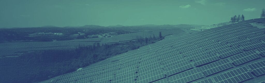 solar panel farm on green hillsides with small community of houses in background